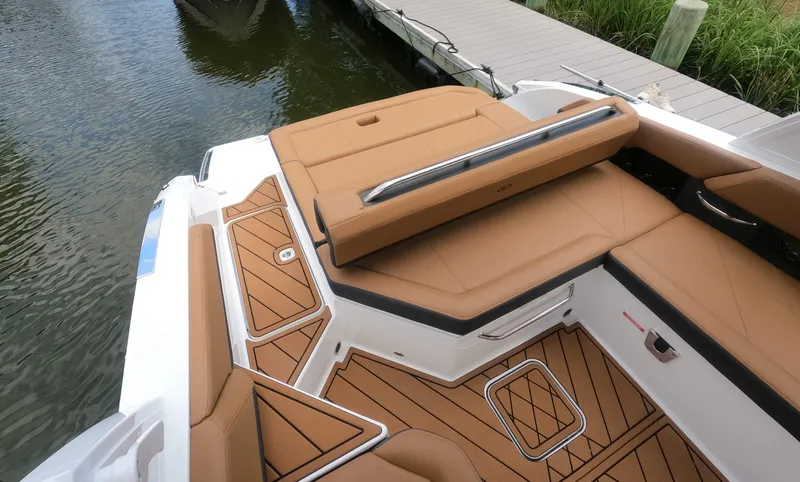 Slide: The Image of 2026 Cobalt R6 boat interior with tan seating and teak-style flooring by a dock. - 7
