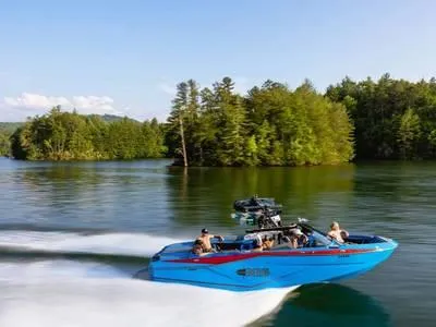 Slide: The Image of 2025 Axis T250 boat speeding on a scenic lake with lush green trees. - 1