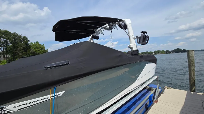 Slide: The Image of 2022 Correct Craft Super Air Nautique G23 boat docked by a lake under a clear sky. - 10