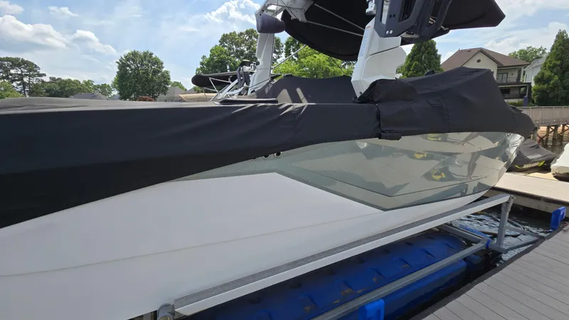 Slide: The Image of 2022 Correct Craft Super Air Nautique G23 boat docked, covered, with clear skies. - 12