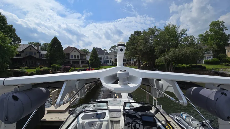 Slide: The Image of 2022 Correct Craft Super Air Nautique G23 boat docked, surrounded by waterfront homes and trees. - 35