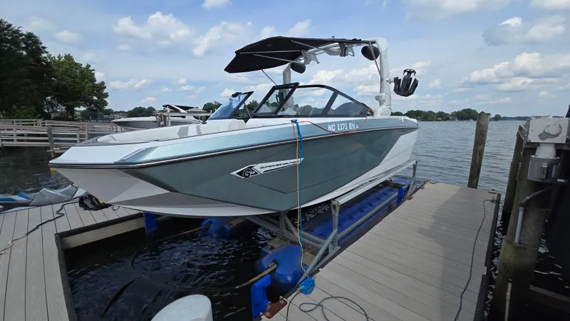 Slide: The Image of 2022 Correct Craft Super Air Nautique G23 boat docked on a lake under a cloudy sky. - 4