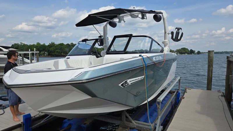 Slide: The Image of 2022 Correct Craft Super Air Nautique G23 boat docked by a lake under a cloudy sky. - 8