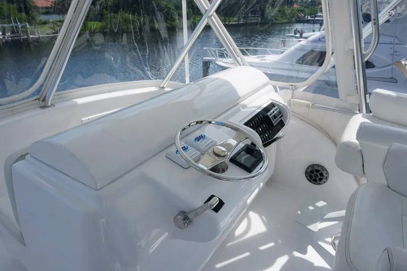 Slide: The Image of Helm of 2005 Mirage Yachts 40 Convertible with steering wheel and controls, docked by water. - 21