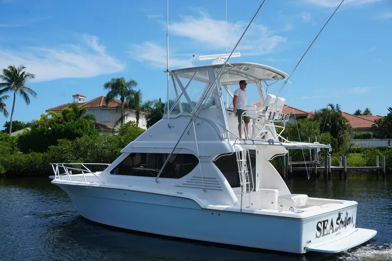 Slide: The Image of 2005 Mirage Yachts 40 Convertible cruising on a sunny day near waterfront homes. - 3