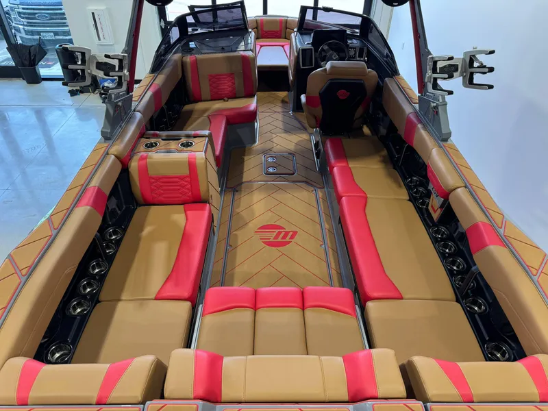 Slide: The Image of 2023 Malibu Wakesetter 26 LSV interior with tan and red seating, cup holders, and steering console. - 13
