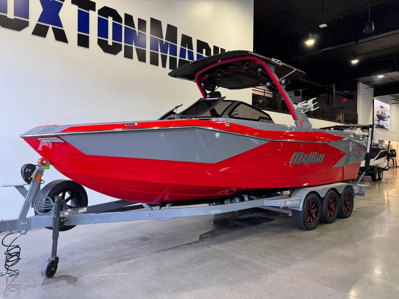 Slide: The Image of 2023 Malibu Wakesetter 26 LSV boat in showroom, red and gray design on trailer. - 2