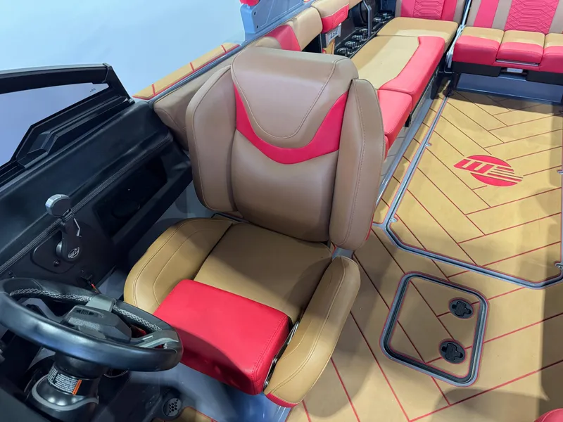 Slide: The Image of 2023 Malibu Wakesetter 26 LSV interior with tan and red seating, steering wheel, and custom flooring. - 21