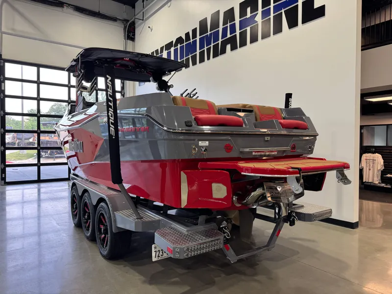 Slide: The Image of 2023 Malibu Wakesetter 26 LSV boat in showroom, red and gray exterior, triple-axle trailer. - 5