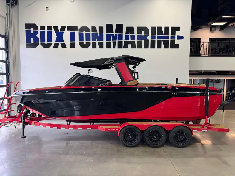 Slide: The Image of 2024 Nautique Super Air Nautique G25 boat in showroom, red and black design on trailer. - 1
