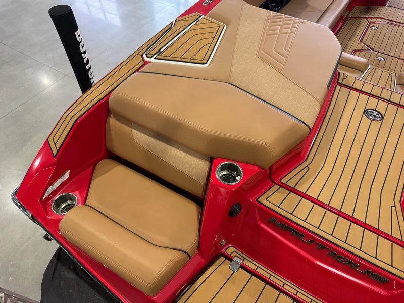 Slide: The Image of 2024 Nautique Super Air Nautique G25 boat interior with tan seating and red accents. - 11