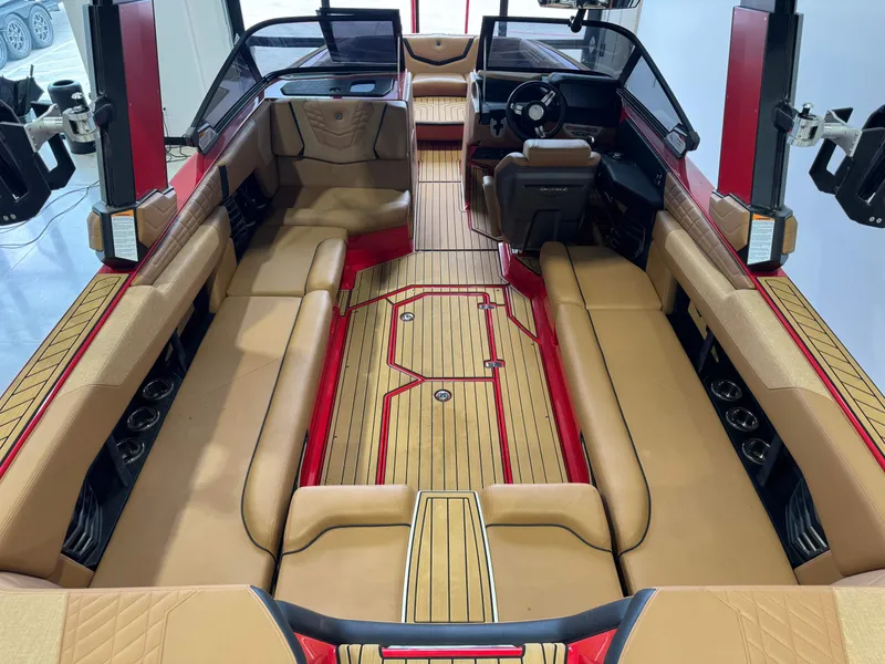 Slide: The Image of 2024 Nautique Super Air Nautique G25 interior with tan seating and red accents. - 12