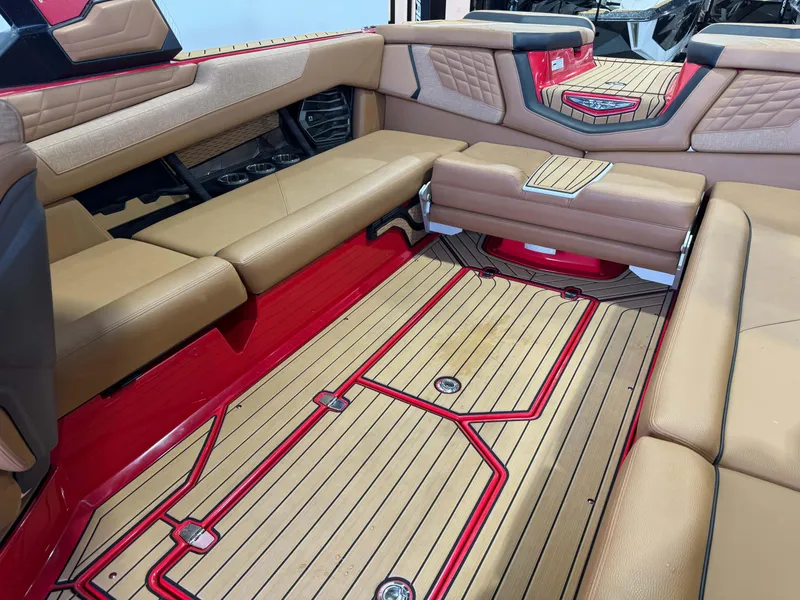 Slide: The Image of 2024 Nautique Super Air Nautique G25 interior with tan seating and red accents. - 14