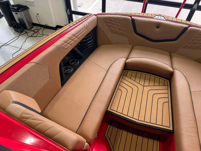 Slide: The Image of 2024 Nautique Super Air Nautique G25 interior with tan seating and red accents. - 18