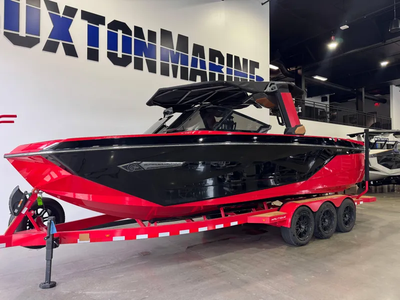 Slide: The Image of 2024 Nautique Super Air Nautique G25 boat in showroom, red and black design on trailer. - 3