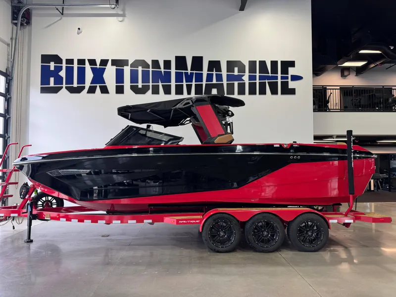Slide: The Image of 2024 Nautique Super Air Nautique G25 boat in showroom, red and black design, on trailer. - 4