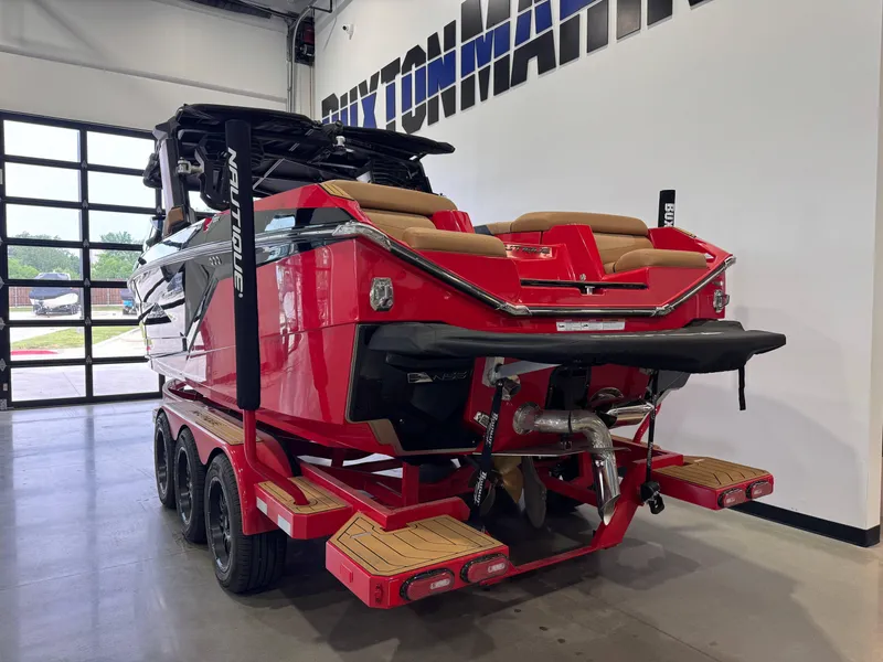 Slide: The Image of 2024 Nautique Super Air Nautique G25 boat in showroom, vibrant red with tan seating. - 5