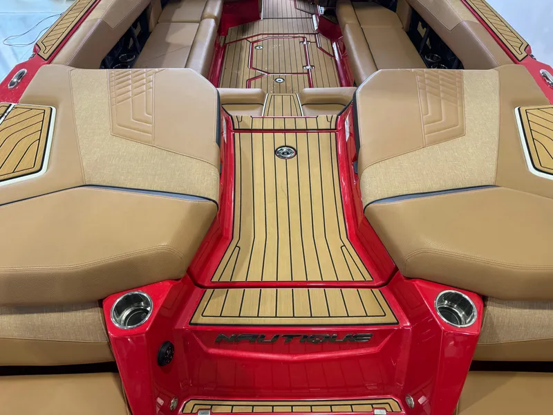 Slide: The Image of 2024 Nautique Super Air Nautique G25 interior with tan seats and red accents. - 9
