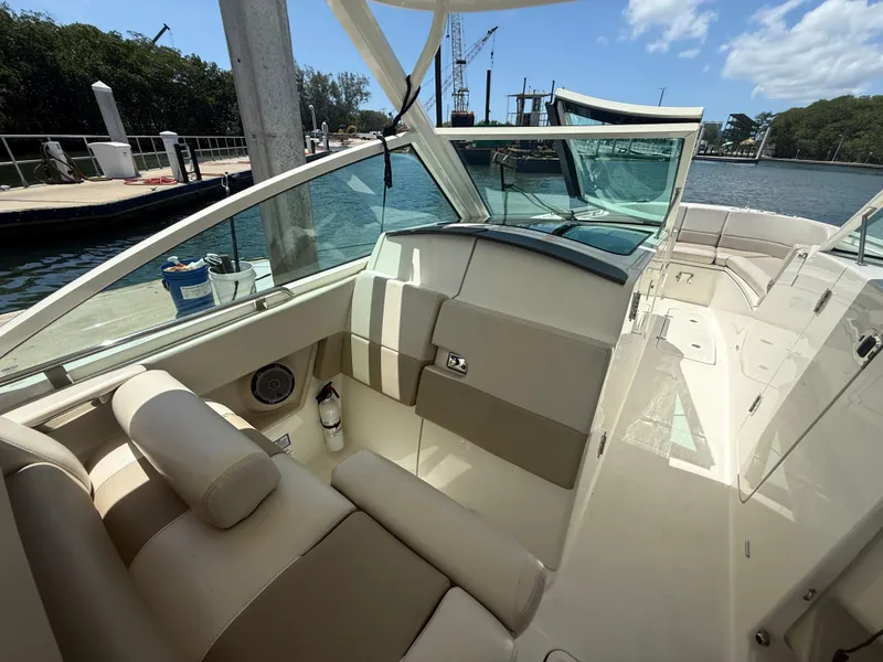 Slide: The Image of 2017 Boston Whaler 320 Vantage boat interior with beige seating and waterfront view. - 15