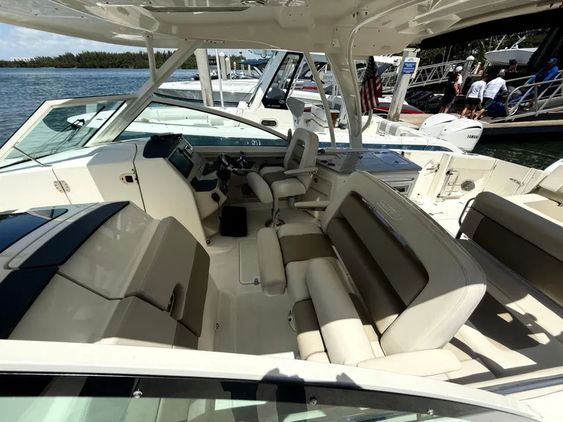 Slide: The Image of 2017 Boston Whaler 320 Vantage boat interior with seating and helm, docked by the water. - 5