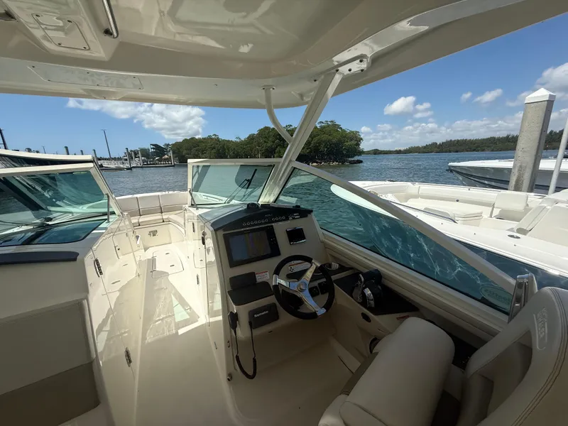 Slide: The Image of 2017 Boston Whaler 320 Vantage boat interior with helm, docked by scenic waterfront. - 6