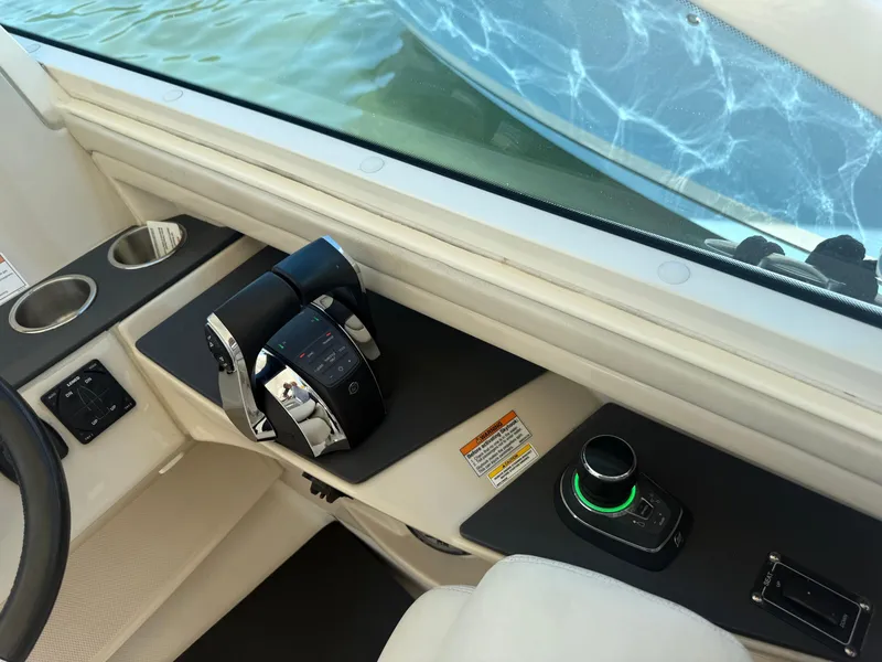 Slide: The Image of 2017 Boston Whaler 320 Vantage helm with controls and cup holders, near water. - 8