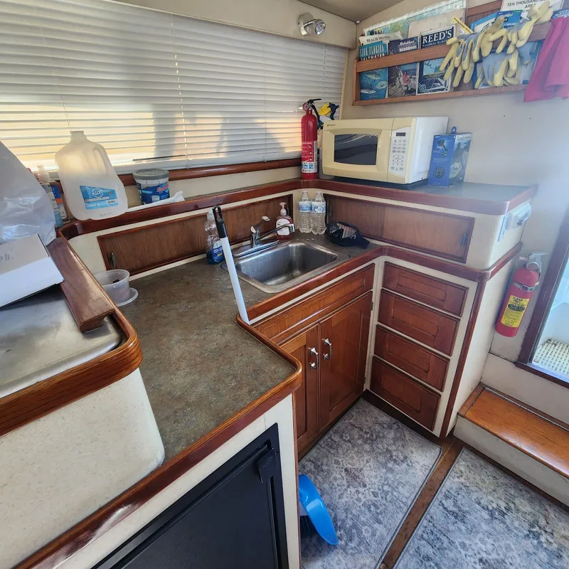 Slide: The Image of 1984 Bertram 30 Express boat kitchen with sink, microwave, and storage cabinets. - 13