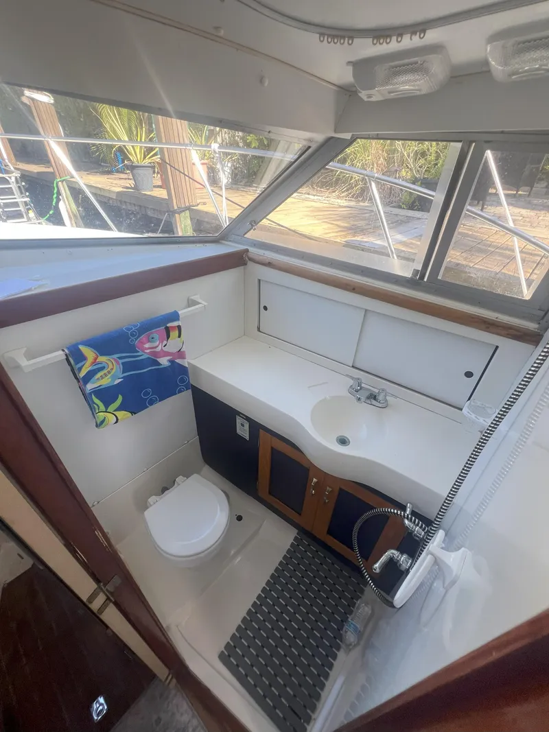Slide: The Image of 1984 Bertram 30 Express boat bathroom with sink, toilet, and window view. - 14