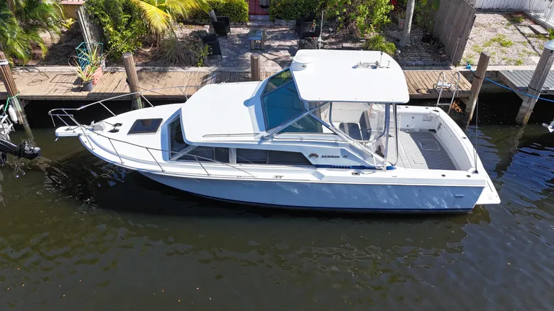 Slide: The Image of 1984 Bertram 30 Express boat docked in a canal, surrounded by lush greenery. - 2