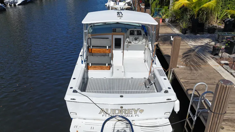 Slide: The Image of 1984 Bertram 30 Express boat docked, rear view, with seating and helm visible. - 3