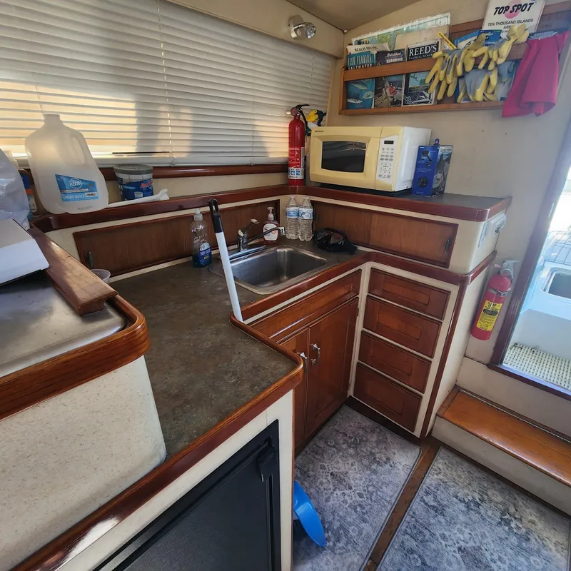 Slide: The Image of 1984 Bertram 30 Express boat kitchen with sink, microwave, and storage cabinets. - 6