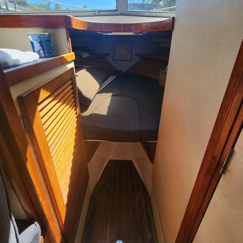 Slide: The Image of 1984 Bertram 30 Express cabin interior with wooden finishes and cozy sleeping area. - 7