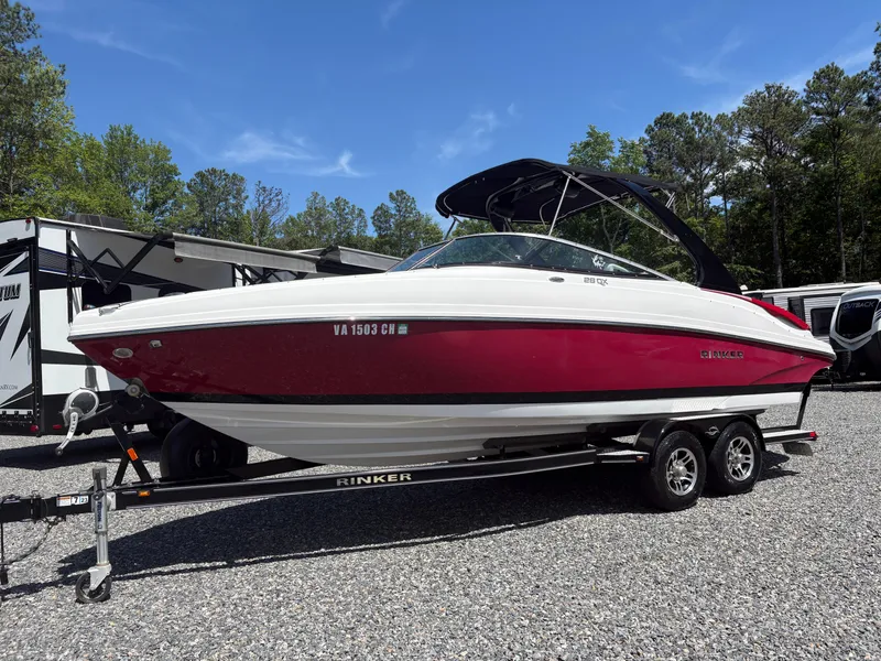 Slide: The Image of 2018 Rinker 26QX BR boat on trailer, red and white, parked outdoors. - 1