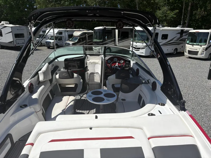 Slide: The Image of 2018 Rinker 26QX BR boat interior with seating, steering wheel, and cup holders, parked near RVs. - 10
