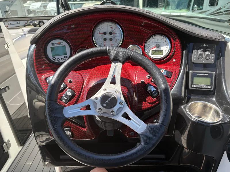 Slide: The Image of Steering wheel and dashboard of 2018 Rinker 26QX BR boat with red accents. - 17