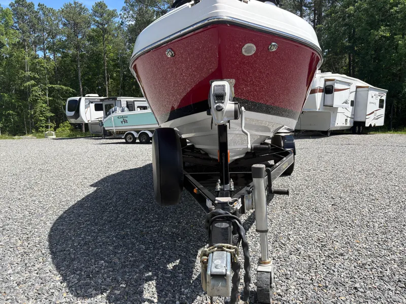 Slide: The Image of 2018 Rinker 26QX BR boat on trailer, parked on gravel with RVs in background. - 36