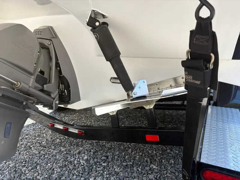 Slide: The Image of 2018 Rinker 26QX BR boat trailer hitch and motor detail on gravel surface. - 7