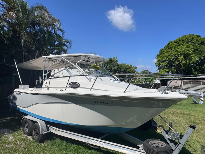 Slide: The Image of 2011 Sea Fox 256 WA Voyager boat on trailer, parked on grass under clear blue sky. - 0