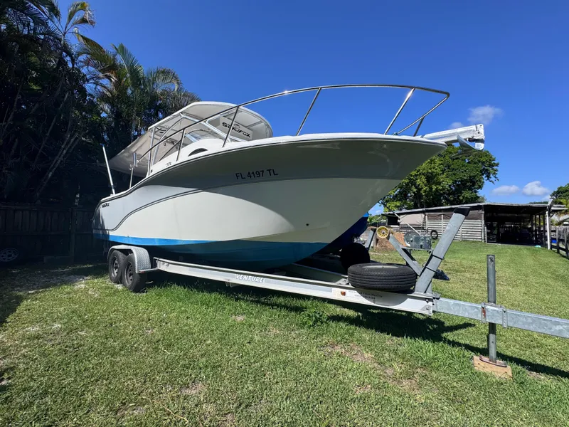 Slide: The Image of 2011 Sea Fox 256 WA Voyager boat on trailer, parked on grass under clear blue sky. - 2