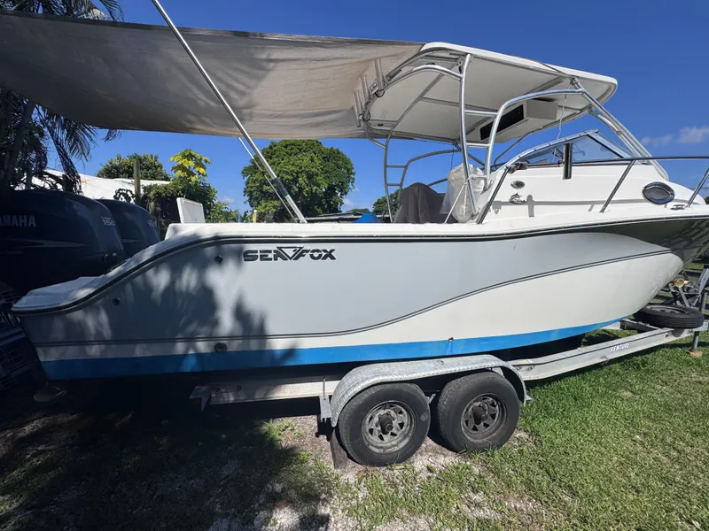 Slide: The Image of 2011 Sea Fox 256 WA Voyager boat on trailer, shaded by canopy, parked on grass. - 5