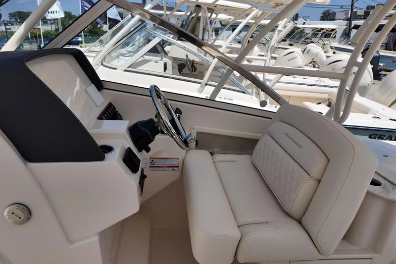 Slide: The Image of 2026 Grady-White Freedom 275 boat interior with steering wheel and cushioned seating. - 17