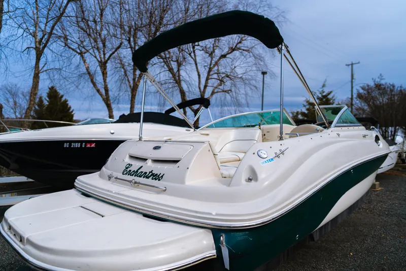 Slide: The Image of 2003 Sea Ray 240 Sundeck boat with canopy, parked outdoors on a cloudy day. - 2
