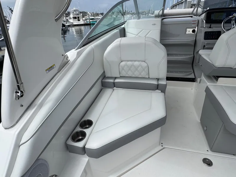 Slide: The Image of 2025 Regal 26 XO boat interior with white seating and cup holders, docked at marina. - 22