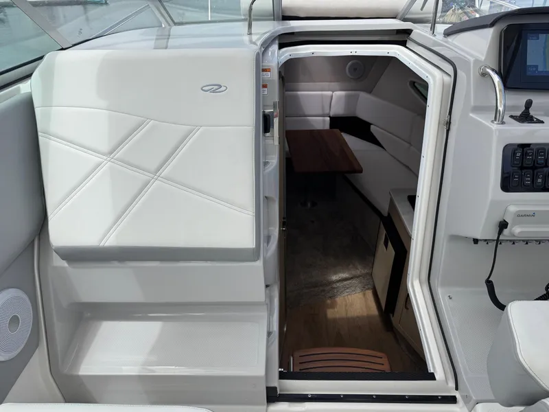 Slide: The Image of 2025 Regal 26 XO boat interior with white seating and wooden table. - 35