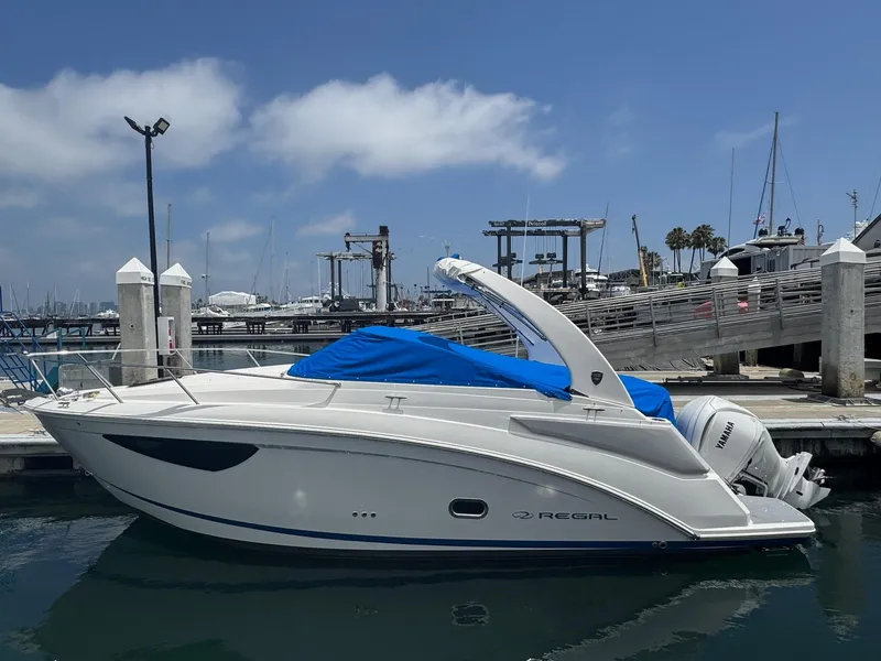 Slide: The Image of 2025 Regal 26 XO boat docked at marina, blue cover, clear sky. - 63