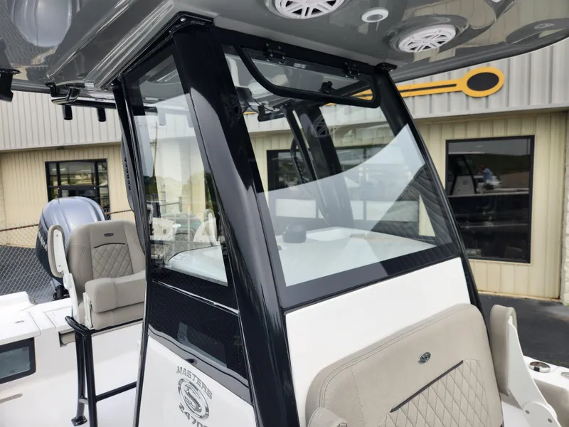 Slide: The Image of 2025 Sportsman Masters 247OE Bay Boat console with seating and windshield, displayed outdoors. - 15