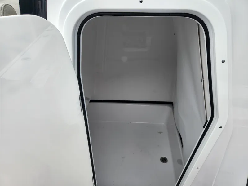 Slide: The Image of 2025 Sportsman Masters 247OE Bay Boat storage compartment, open door, white interior. - 19