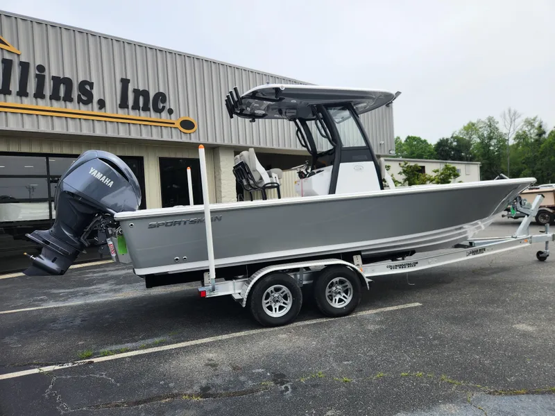 Slide: The Image of 2025 Sportsman Masters 247OE Bay Boat on trailer, parked outside a building. - 2