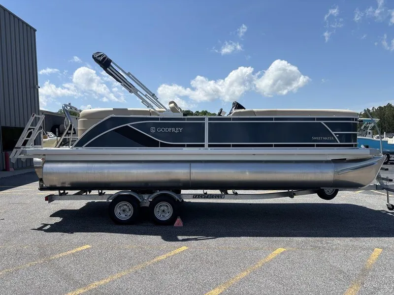 The Image of 2025 Godfrey SWEETWATER 2286 SB pontoon boat on trailer, parked outdoors. - 0