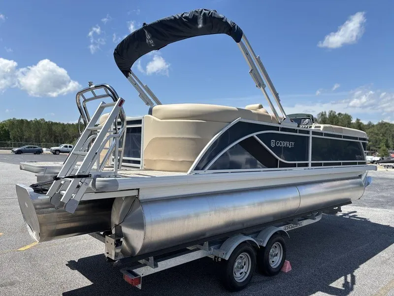 Slide: The Image of 2025 Godfrey SWEETWATER 2286 SB pontoon boat on trailer, sunny day, blue sky. - 19